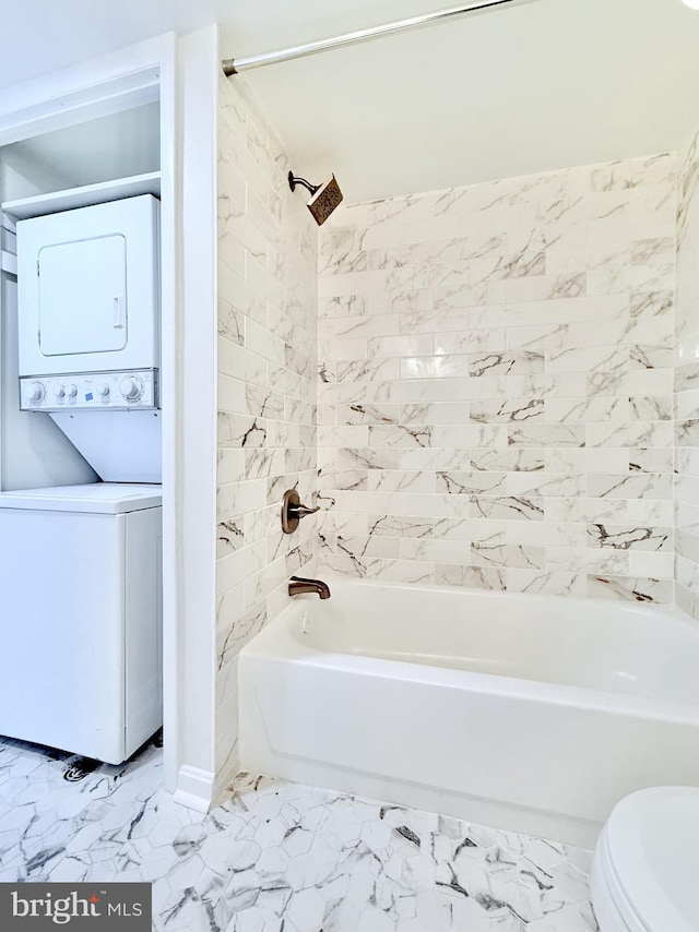 full bath with toilet, marble finish floor, bathtub / shower combination, and stacked washer and clothes dryer