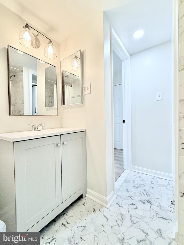 bathroom featuring marble finish floor, vanity, and baseboards