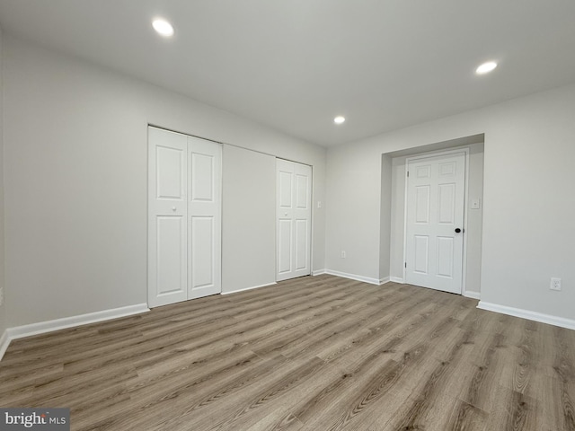 unfurnished bedroom featuring recessed lighting, a closet, baseboards, and wood finished floors