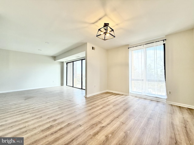 empty room featuring plenty of natural light, wood finished floors, and baseboards