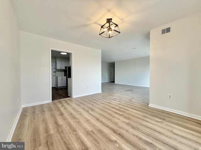 unfurnished room with light wood-style floors, visible vents, and baseboards