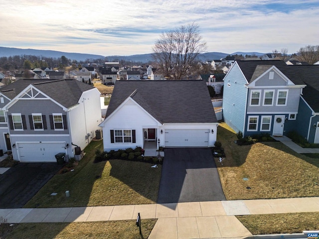 view of front facade with an attached garage, a mountain view, driveway, a residential view, and a front yard