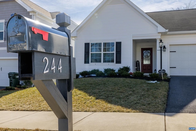 view of front facade with a garage, aphalt driveway, and a front yard