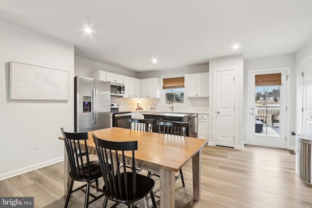 dining room featuring light wood-style flooring, baseboards, and recessed lighting