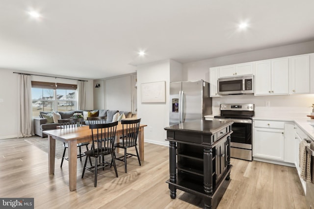 kitchen with stainless steel appliances, white cabinets, and light wood-style flooring