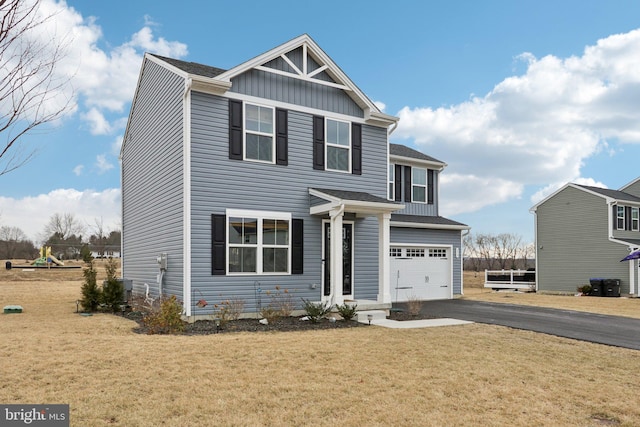 view of front of home with a shingled roof, aphalt driveway, an attached garage, a front lawn, and board and batten siding