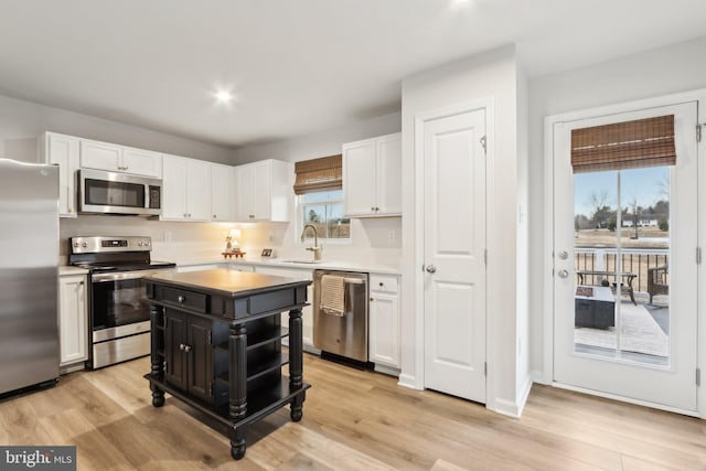 kitchen featuring a sink, white cabinets, light countertops, appliances with stainless steel finishes, and light wood finished floors