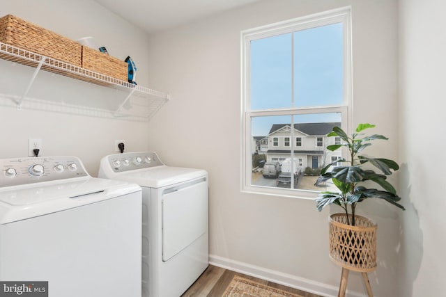 clothes washing area with laundry area, washer and clothes dryer, baseboards, and wood finished floors