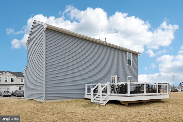 back of house featuring a wooden deck and a yard