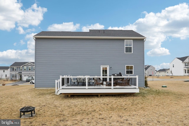 back of property featuring an outdoor fire pit, a residential view, a deck, and a yard