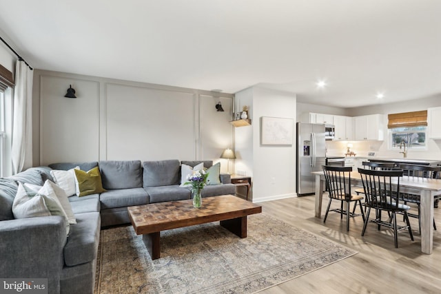 living area with light wood-style flooring, baseboards, and recessed lighting