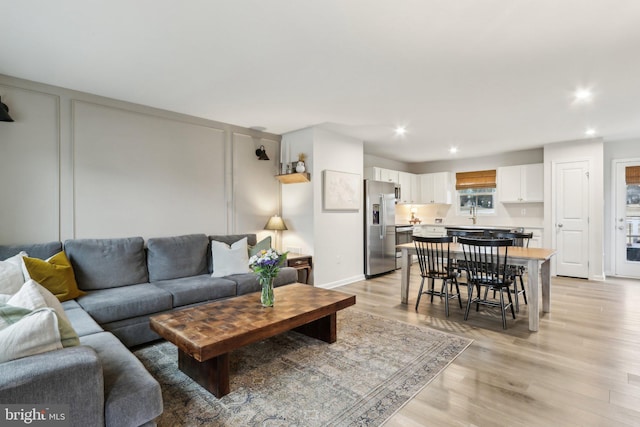 living area with light wood-style floors, recessed lighting, and baseboards