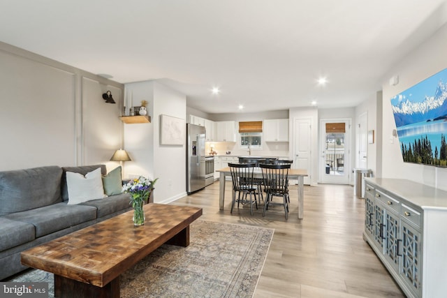 living area with light wood-type flooring, baseboards, and recessed lighting