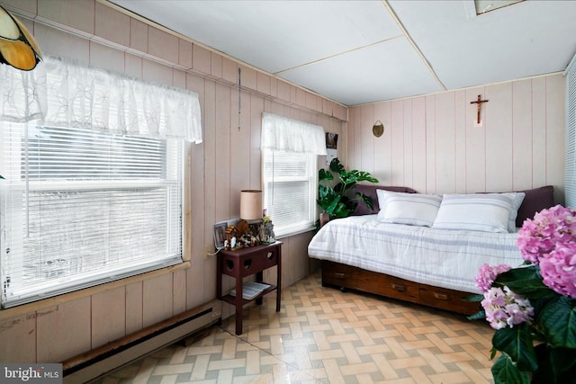 bedroom featuring a baseboard heating unit and multiple windows