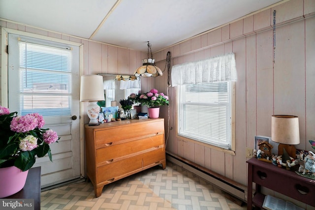 dining area with a baseboard radiator and wood walls