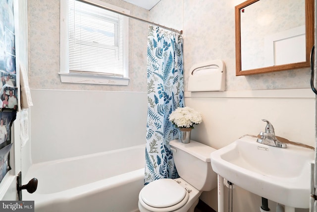 full bath featuring wallpapered walls, toilet, shower / tub combo, and a sink