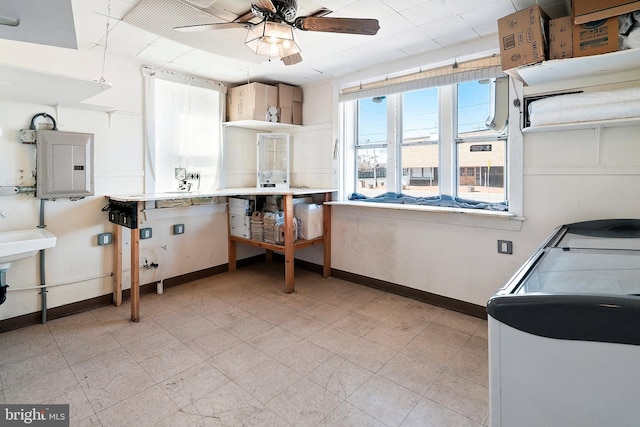 kitchen with electric panel, baseboards, and a ceiling fan