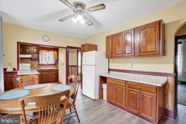 kitchen with under cabinet range hood, range, light countertops, and freestanding refrigerator