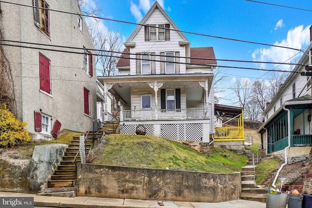 view of front of property with stairs, covered porch, and a balcony