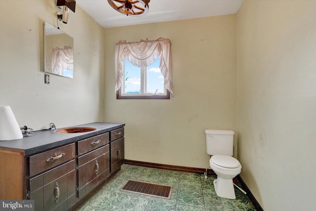 half bathroom with toilet, visible vents, baseboards, and vanity