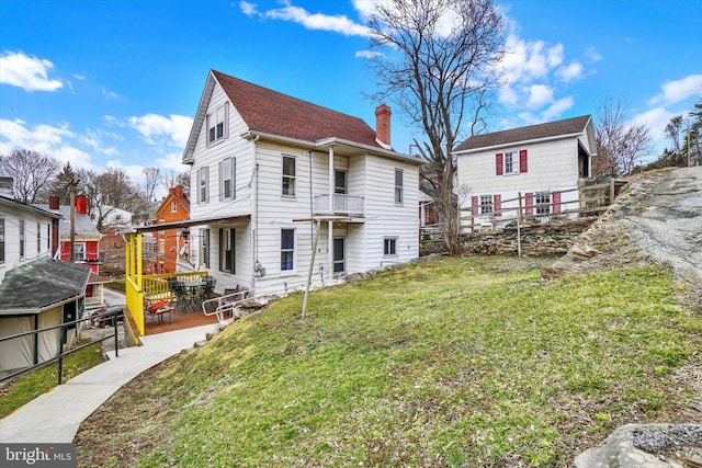 back of property with a lawn, a chimney, and fence