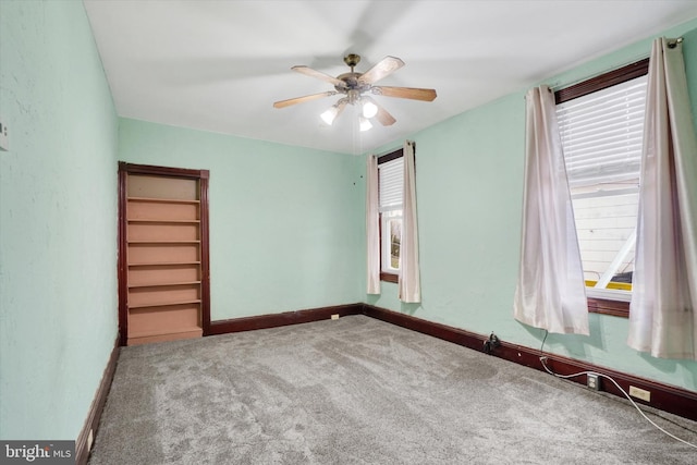 carpeted spare room featuring a ceiling fan and baseboards