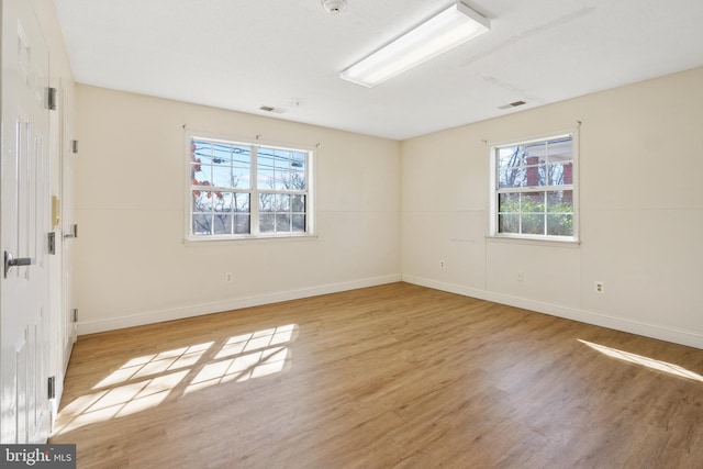 spare room with light wood-style flooring, visible vents, and baseboards