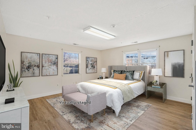 bedroom with visible vents, baseboards, and wood finished floors