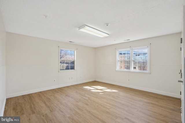 unfurnished room with baseboards, a healthy amount of sunlight, and light wood finished floors