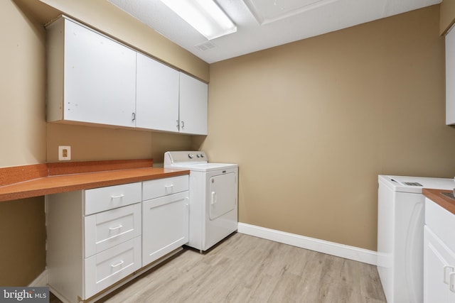 washroom with washer / dryer, cabinet space, light wood-style floors, and baseboards