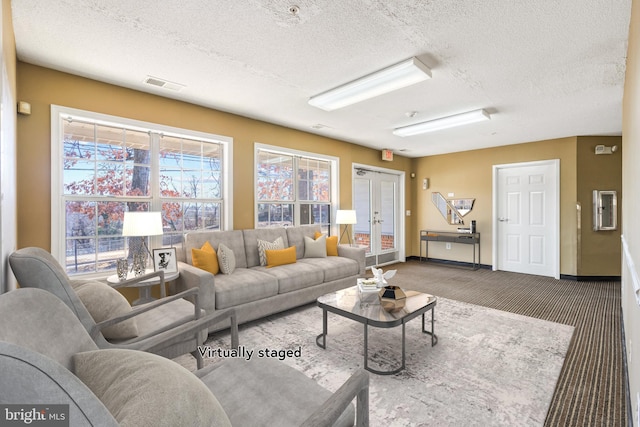 carpeted living area with a textured ceiling, french doors, visible vents, and baseboards