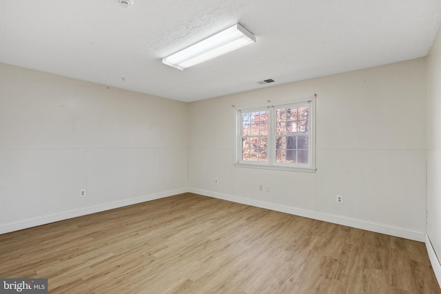 spare room featuring visible vents, baseboards, and wood finished floors