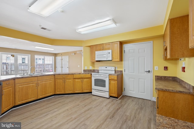 kitchen with visible vents, light wood-style floors, brown cabinetry, a sink, and white appliances