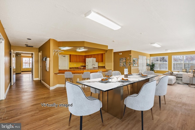 dining area featuring light wood-style flooring, baseboards, and a textured ceiling