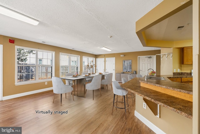 dining room with light wood-style flooring, baseboards, and a textured ceiling