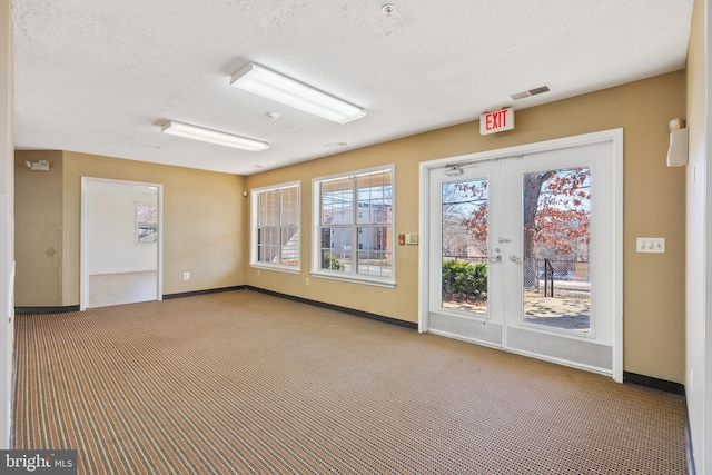 interior space with french doors, visible vents, carpet flooring, a textured ceiling, and baseboards