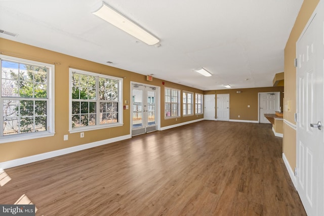 unfurnished living room featuring french doors, wood finished floors, visible vents, and baseboards