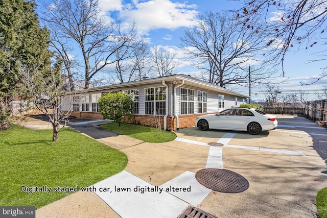 view of front of property featuring brick siding, fence, and a front lawn