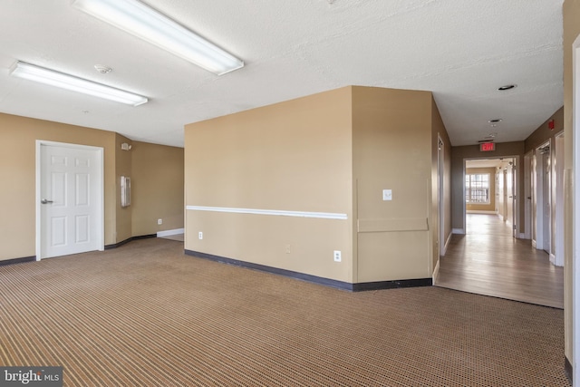 empty room featuring a textured ceiling, baseboards, and carpet flooring