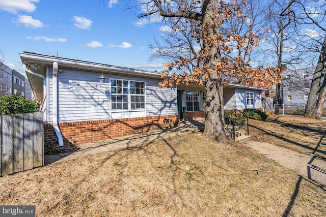 rear view of property with a yard, brick siding, and fence