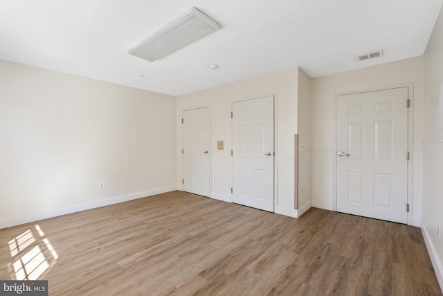 unfurnished bedroom with light wood finished floors, baseboards, and visible vents