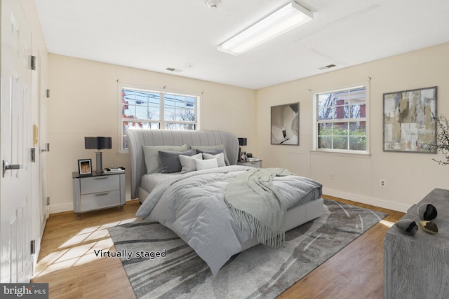 bedroom with visible vents, baseboards, and wood finished floors