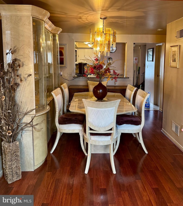 dining room featuring baseboards, wood finished floors, visible vents, and a notable chandelier