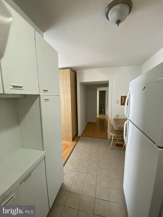 kitchen featuring light tile patterned floors, white cabinetry, light countertops, and freestanding refrigerator