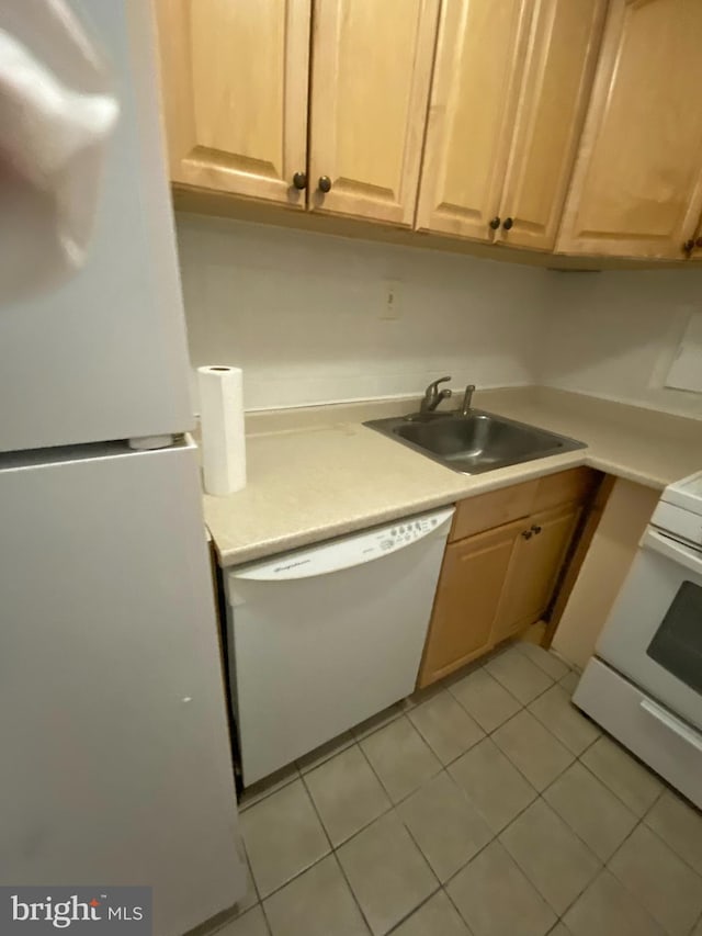 kitchen with light tile patterned floors, light countertops, white appliances, and a sink