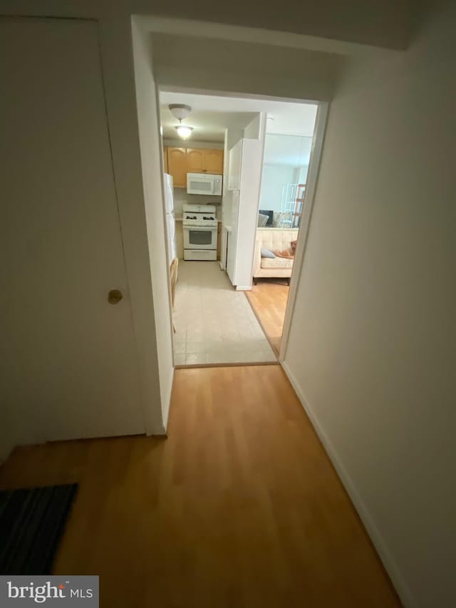 hallway featuring baseboards and light wood-style floors