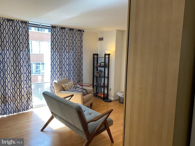 living area with light wood-style flooring and a wall of windows