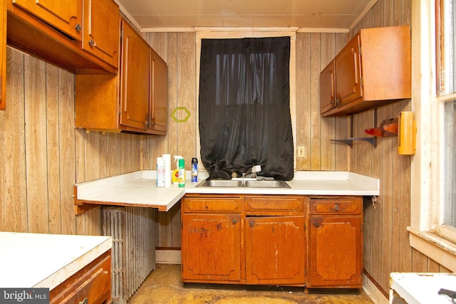 kitchen featuring wood walls, light countertops, a sink, and brown cabinetry