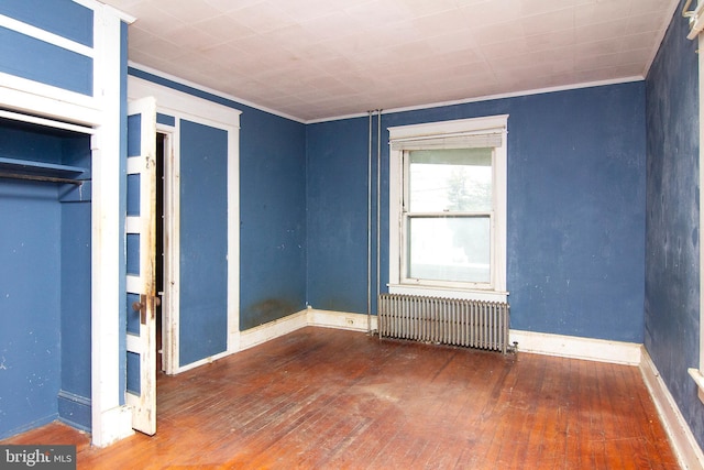 unfurnished bedroom with ornamental molding, radiator, baseboards, and hardwood / wood-style floors