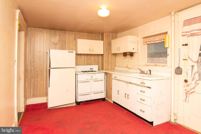 kitchen featuring freestanding refrigerator, light countertops, a sink, and wood walls